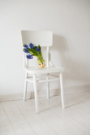 Spring flowers, blue hyacinth in a vase on a white vintage chair in white room interior.の写真素材