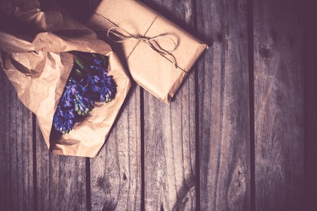Spring flowers and wrapped gift, blue hyacinth on a vintage wooden board background.の写真素材