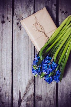 Spring flowers and wrapped gift, blue hyacinth on a vintage wooden board background.の写真素材