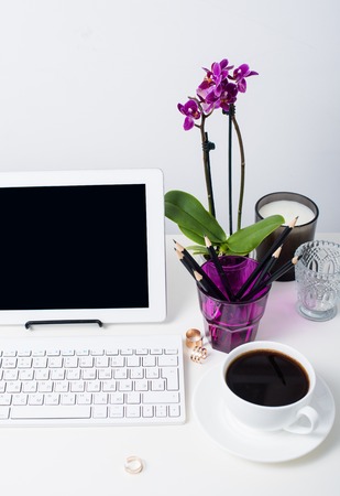 Young business woman workspace, white feminine office interior closeup, orchid flowers and laptop on a table.の写真素材