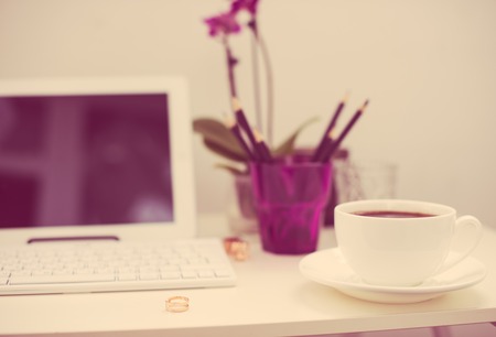 Modern office interior closeup, cup of coffee and computer keyboard. Business objects on white working table, hipster styleの写真素材