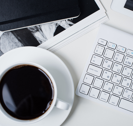 Modern office interior closeup, cup of coffee and computer keyboard. Business objects on white working table background.の写真素材