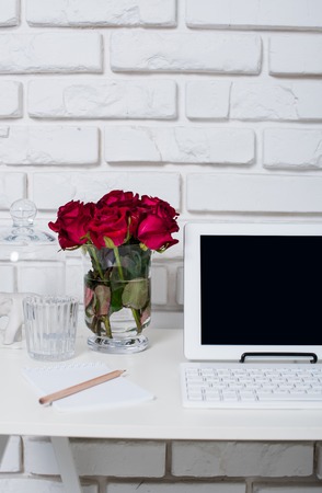 Young business woman workspace, white feminine office interior closeup, roses flowers, cup of coffee  and laptop on a table.の写真素材