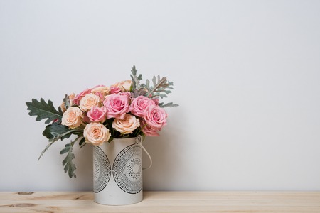 Bouquet of pink and beige roses in a decorative vase on a shelf in home interior, simple home decorの写真素材