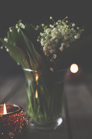 Simple home decoration, lilies of the valley in a vase on a rustic table, dark moody still lifeの写真素材