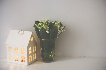Simple home decoration, lilies of the valley in a vase on the shelf by the white wall backgroundの写真素材