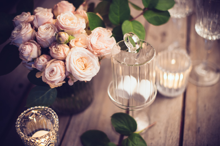 Elegant vintage wedding table decoration with roses and candles, warm night light filterの写真素材