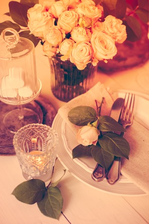Beautiful vintage wedding table decorations with roses, candles, cutlery and  sweets in a jar.の写真素材