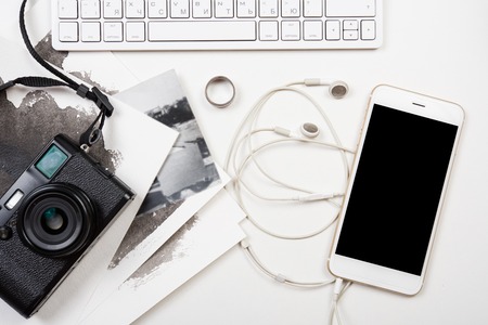 Styled tabletop with computer keyboard, smartphone and retro camera on white background,...