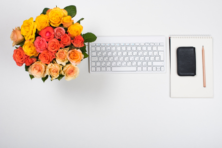 Feminine startup concept, office desk workspace with roses, computer keyboard and notepad on white background. Hipster style mockup.の写真素材