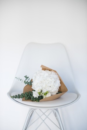 Bouquet of white hydrangeas on a chair by the wallの写真素材