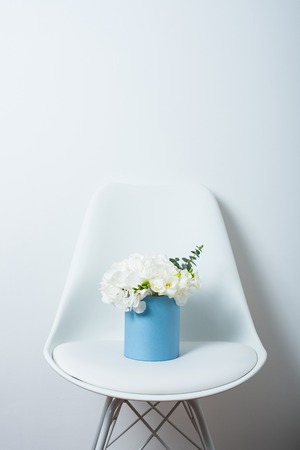 Bouquet of white hydrangeas in a box on a chair by the wallの写真素材