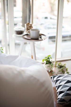 Coffee served on table in bright light scandinavian style hipster interior, cozy loft room with large windows closeupの写真素材