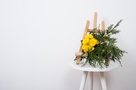 Arrangement of flowers and branches on a table near white wall backgroundの写真素材