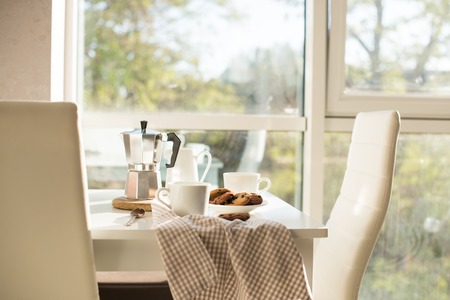 Early morning french home breakfast, coffee and cookies on the table near window in bright sunlight,...