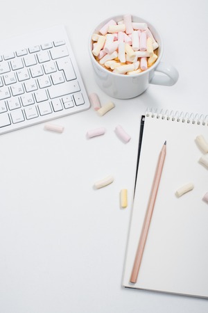 White feminine hipster workspace background, styled womans office table with coffee and marshmallowsの写真素材