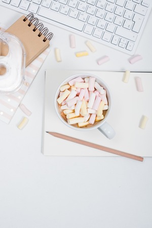 White feminine hipster workspace background, styled womans office table with coffee and marshmallowsの写真素材