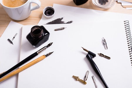 Artist's desk and workspace. Paper, ink and calligraphy pens. Creative process, lettering art workshop details close-up.の写真素材