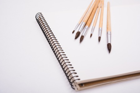 Watercolor paint brushes and clean paper on artist's work desk, isolated on white backgroundの写真素材