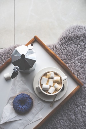 Warm cozy home. Tray and cup of coffee with marshmallows on a floor, comfortable indoorsの写真素材