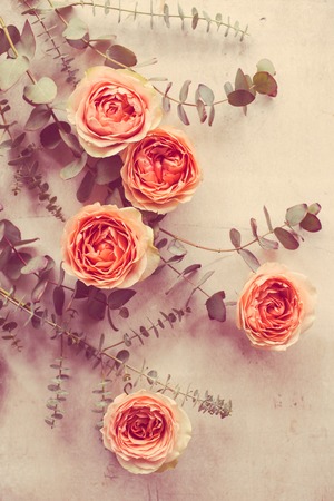 Orange roses and decorative branches on white textured tableの写真素材