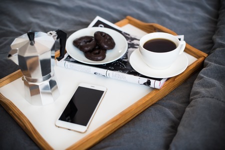 Coffee and breakfast in bed, smartphone and magazine