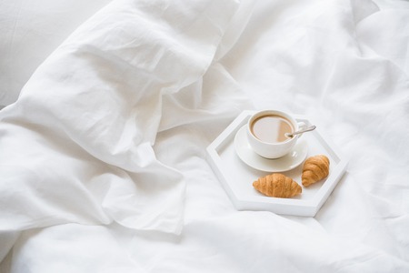Early morning breakfast in bed, coffee and croissant on the trayの写真素材