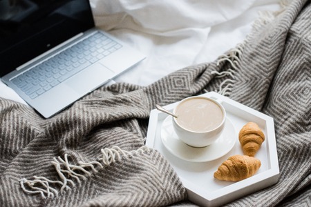Cozy weekend at home, laptop and coffee in bed