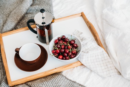 Fresh healthy vegan breakfast in bed, green tea and cherry in moの写真素材
