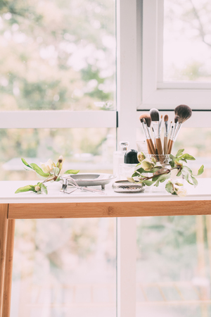Perfumery and cosmetics on a dressing table in daylight, flowers and jewelery on a trayの写真素材