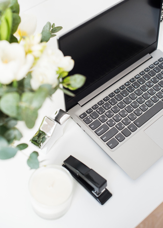 Hipster bloggers work place, laptop and flowers on white tabletopの写真素材