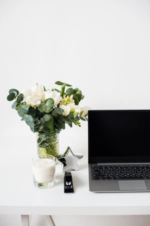 Hipster bloggers work place, laptop and flowers on white tabletopの写真素材