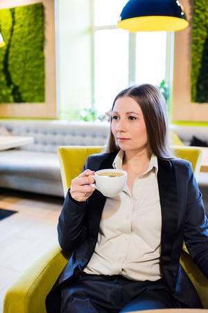 Young business lady drinking herbal tea in city cafe