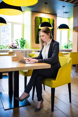 Young business woman working with laptop on the table in the city cafe interiorの写真素材
