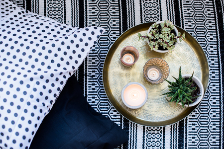 Real apartment interior decor, aromatic candles and plants on vintage tray with pillows and carpet on the floorの写真素材