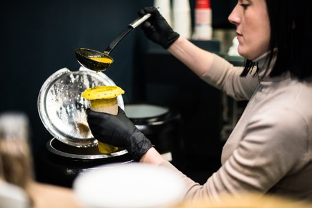 Young lady kitchen worker pours soup into cup