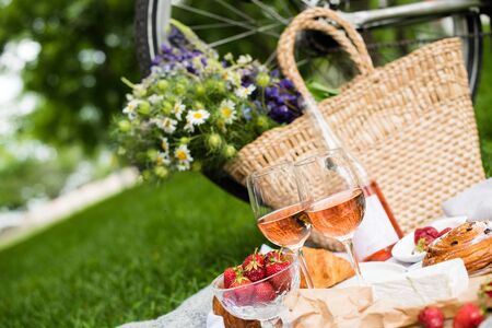 Beautiful summer picnic with strawberries, cheese and rose wine on the lawn in the city parkの写真素材