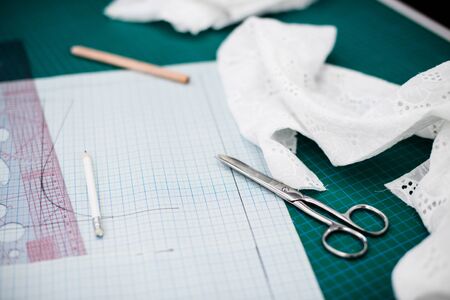 Tools, patterns and fabric samples on the sewing table in the tailor workshop