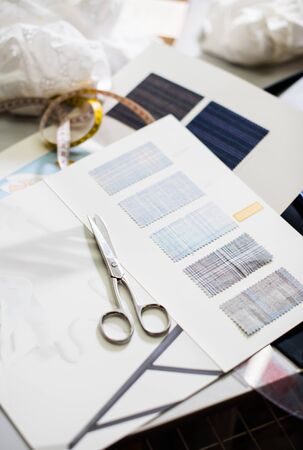 Tools, patterns and fabric samples on the sewing table in the tailor workshopの写真素材
