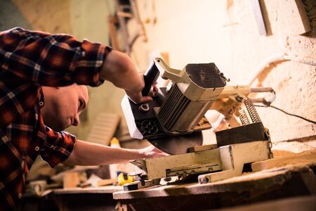Young handsome joiner working with wood in his carpentry workshopの写真素材