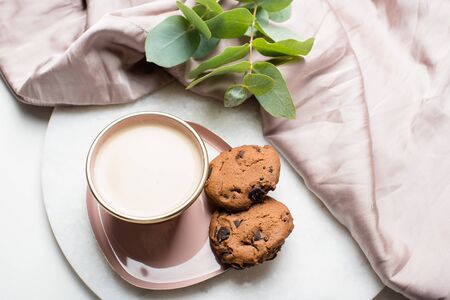 Beautiful enameled cup of coffee with cookies and silk clothの写真素材