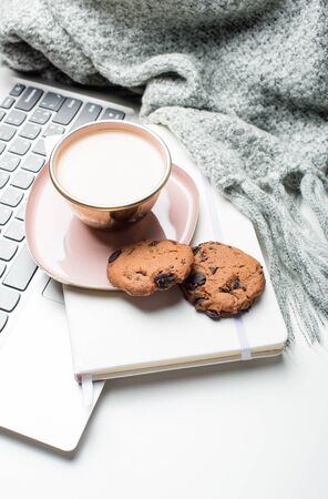 Beautiful enameled pink cup of coffee with blanket and laptopの写真素材