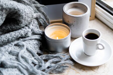 Burning candles, gray blanket and cup of coffee, cozy simple Scandinavian home decoration close-up