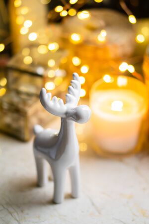 Little white ceramic Christmas deer figurine with yellow holiday lightsの写真素材