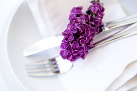 Springtime table setting with lilac branch on white linen napkin, home dinner table decor close-upの写真素材