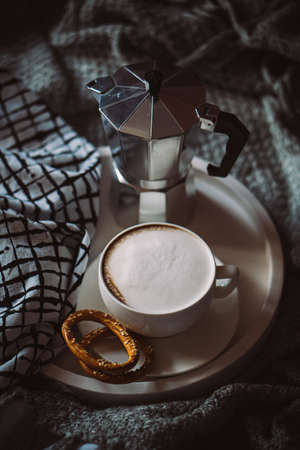 Cup of coffee on tray in cozy winter bad with wool blanketの写真素材