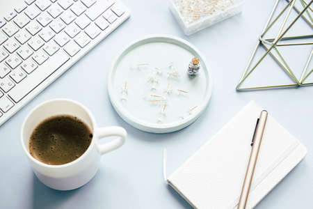 Lady freelancers home pastel blue workplace, cup of coffee and computer keyboard on tabletopの写真素材