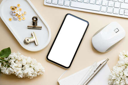 Neutral color tabletop with keyboard, lilac flowers and smartpohone mock-up with white screen...