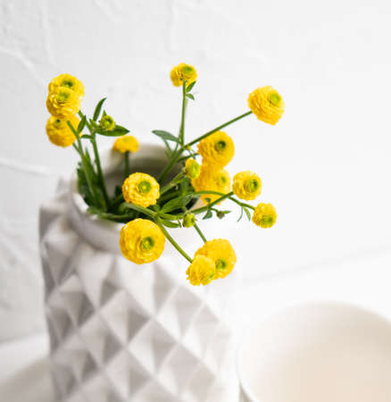White home decoration with yellow flowers, ceramic vase and glass on trayの写真素材