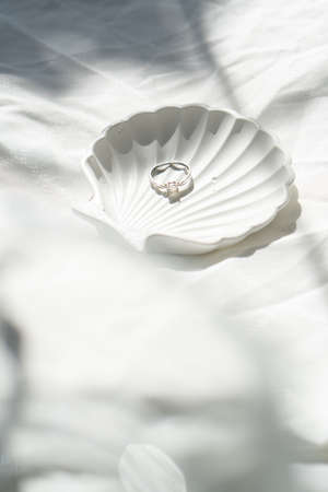 Engagement ring in shell-shaped jewelry plate on textured linen background